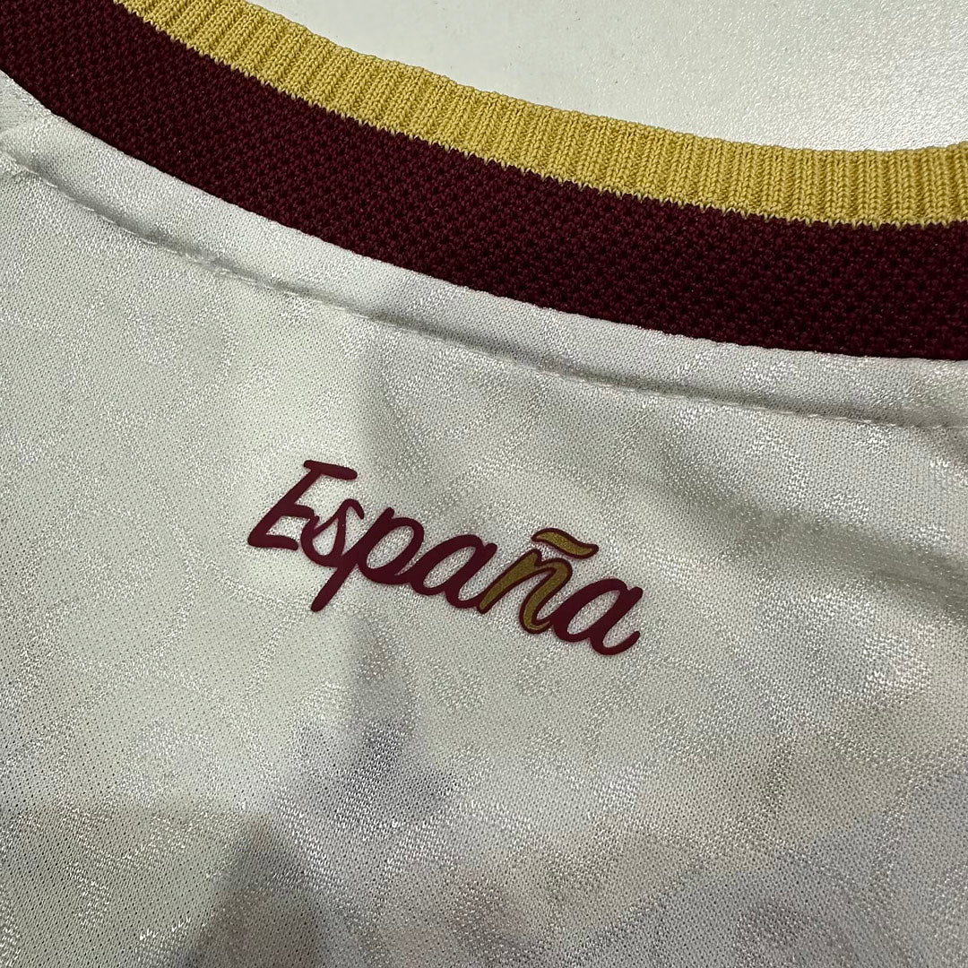 Camiseta Perla - Detalle cuello en V con ribete doble granate y dorado y tres rayas en hombro